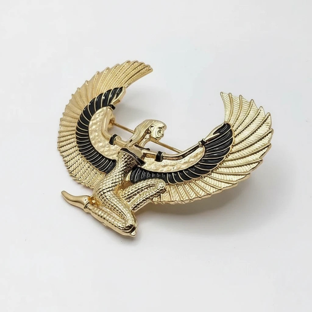 Pins & Co. gold-tone Egyptian winged goddess brooch with black enamel wing accents on a white background.