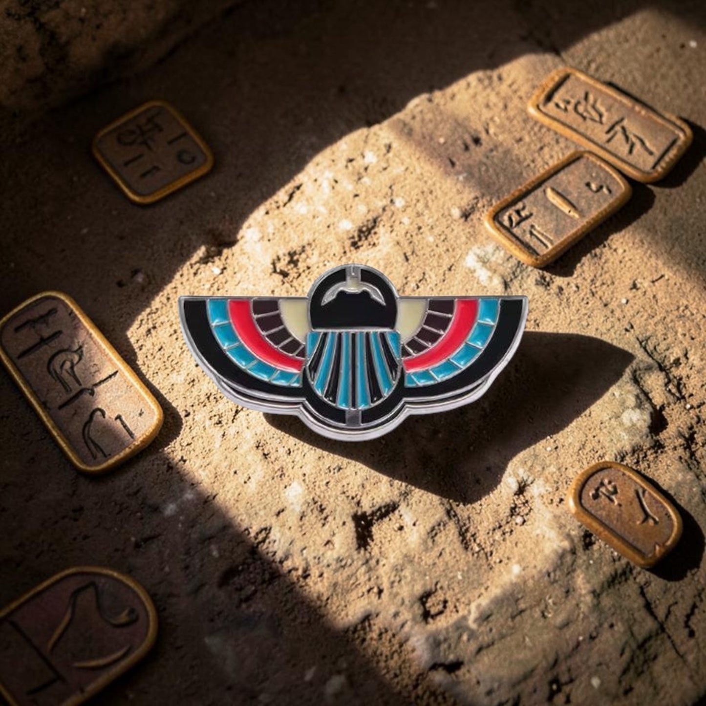 Pins & Co. Egyptian winged scarab brooch in black, red, and turquoise enamel with a polished metal finish.
