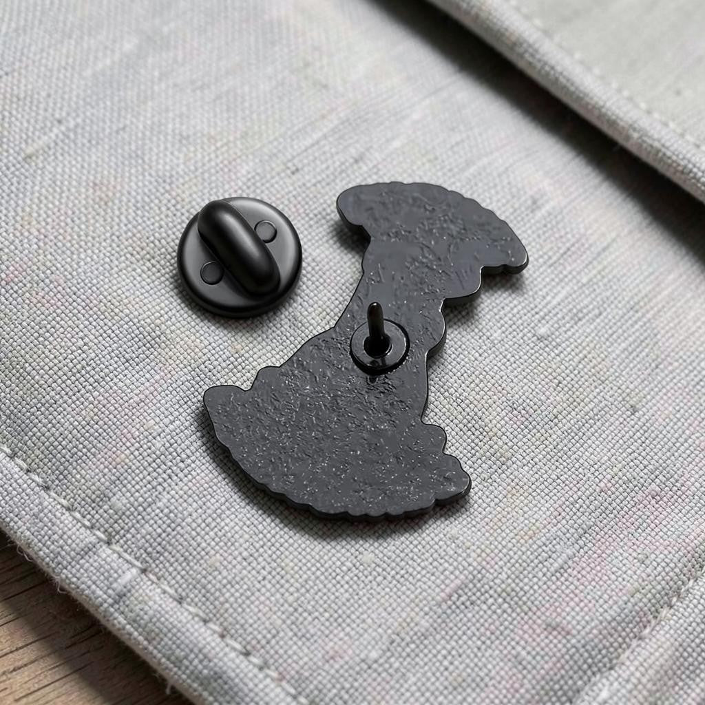 Pins & Co. black metal enamel pin back with secure clutch backing on a light grey fabric surface