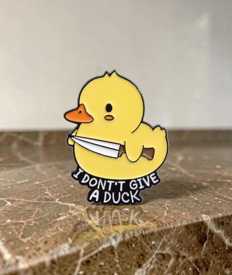 Pins & Co. yellow duck enamel lapel pin holding a knife with the text I Don't Give A Duck in black
