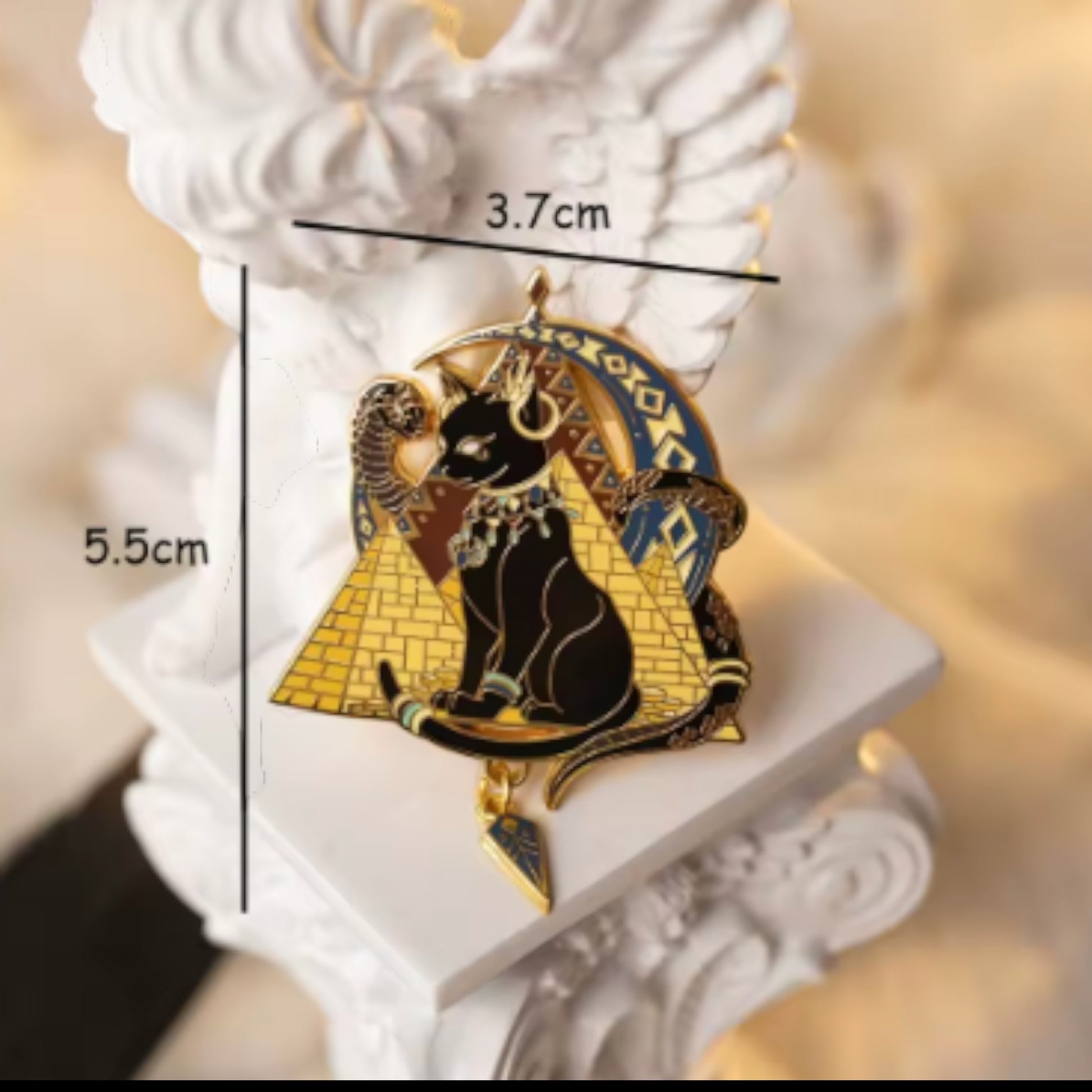Pins & Co. Egyptian cat goddess enamel pin featuring a black cat, gold pyramid, crescent moon, and dangling charm.