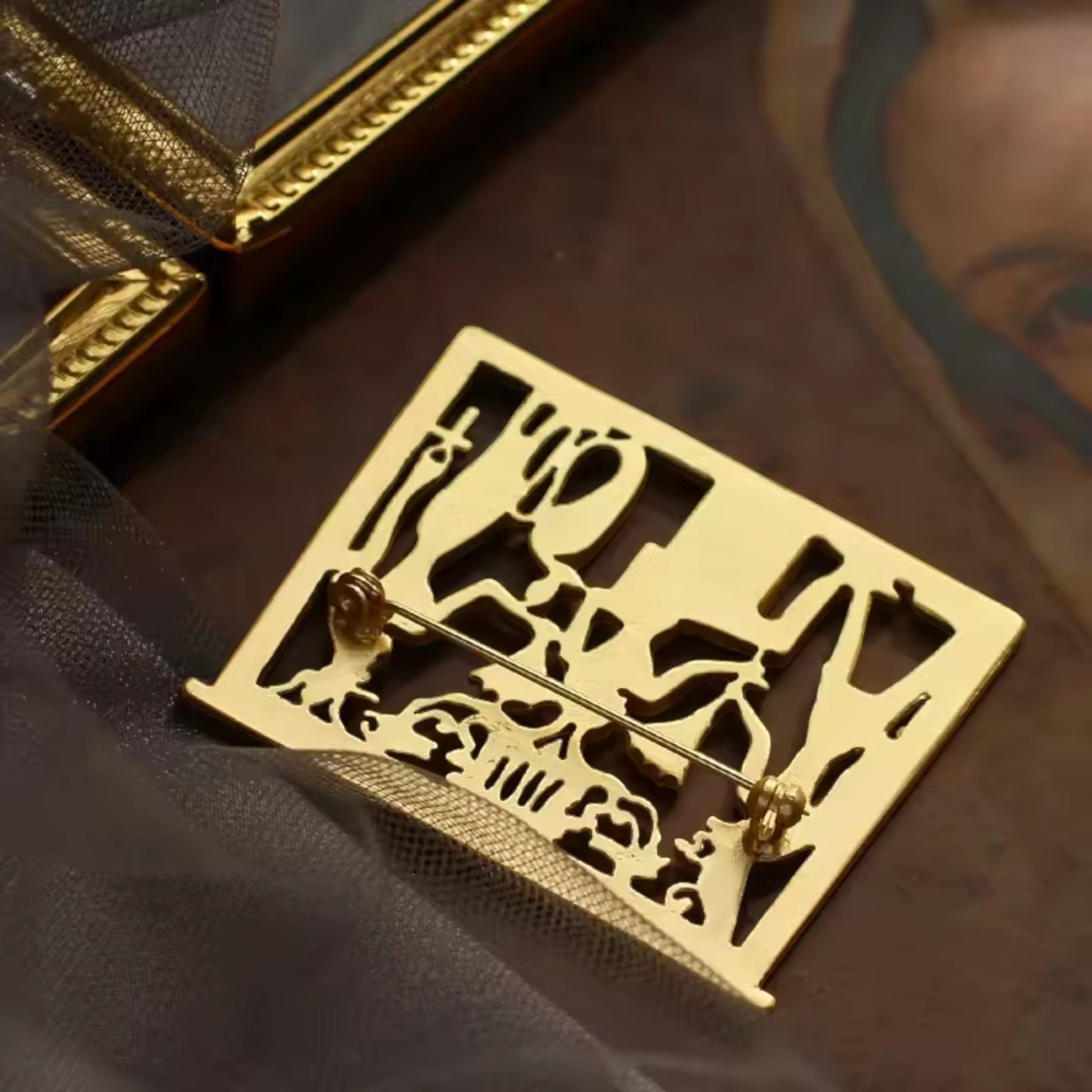 Pins & Co. gold-tone Egyptian-themed metal brooch featuring intricate cut-out hieroglyphic and deity motifs.