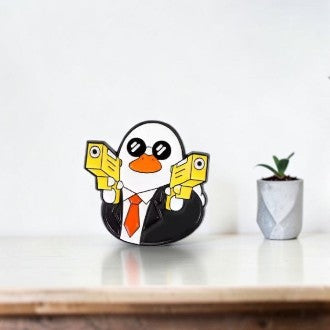 Pins & Co. Secret Agent Duck enamel pin featuring a duck in a black suit, orange tie, sunglasses, and yellow pistols.